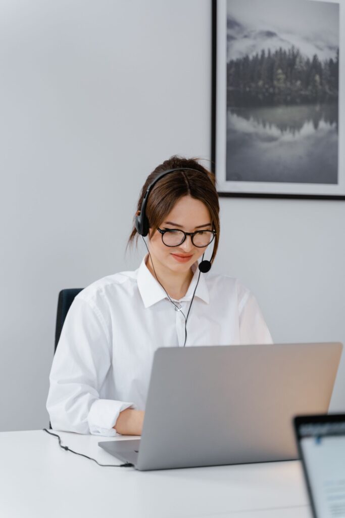 Mujer atendiendo a clientes con portátil y auriculares