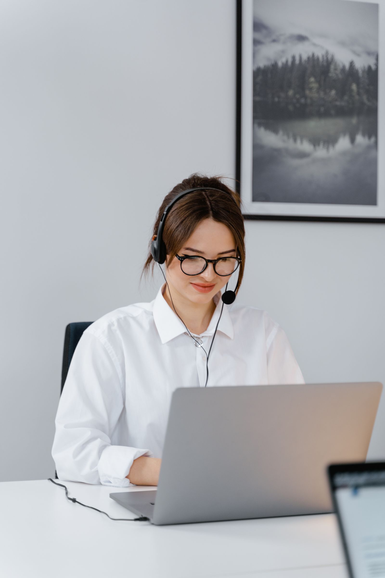 Mujer atendiendo a clientes con portátil y auriculares